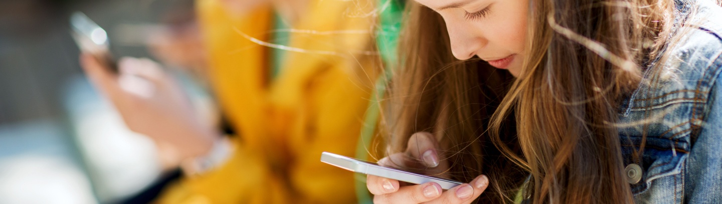 A group of teenagers focused on their cell phones. 