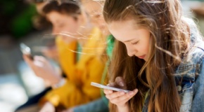 A group of teenagers focused on their cell phones. 