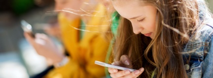 A group of teenagers focused on their cell phones. 