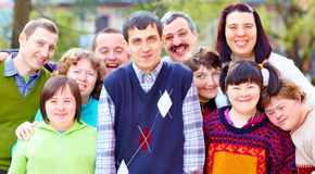 Ten people with disabilities smile and stand together. 